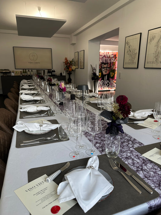 Lange weiß gedeckte Tafel für eine private Feier bei Vino Vista in Hilden, mit Weingläsern, Stoffservietten, Blumen und Menükarten